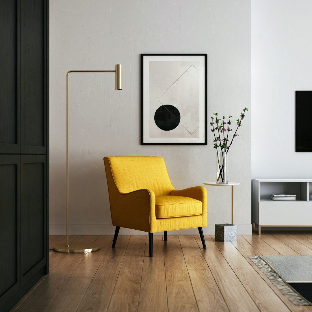 Modern living room with a yellow armchair, floor lamp, framed artwork, and minimalist side table.
